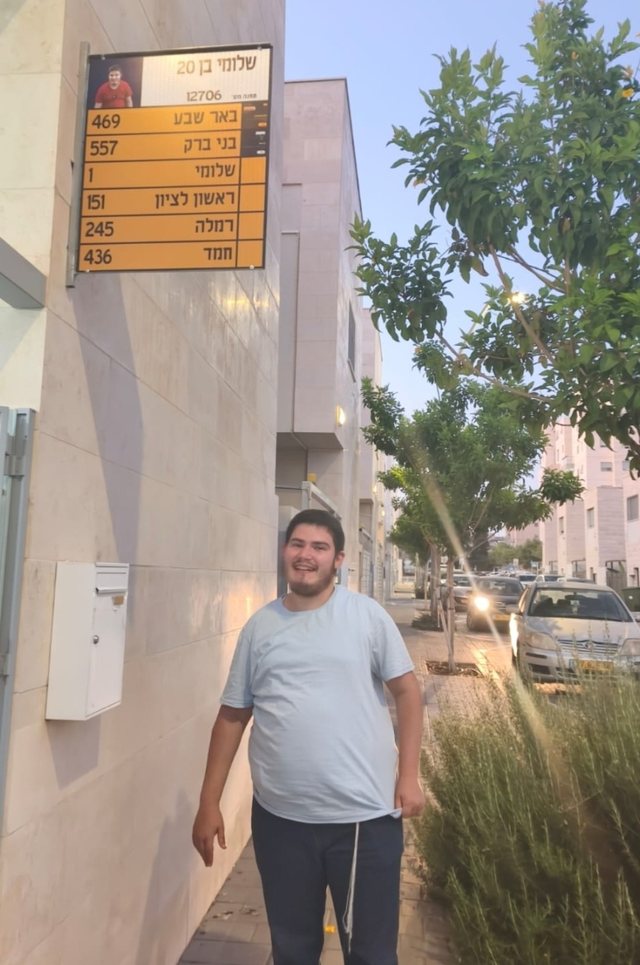 שלומי ליד שלט תחנה אישי שקיבל ליום הולדתו